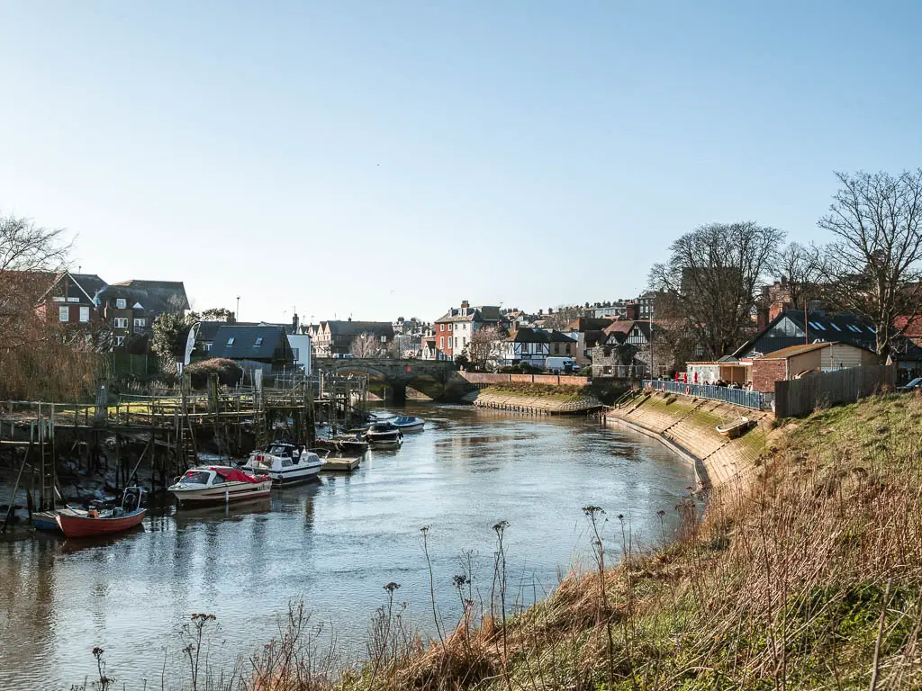 A bend in the River Arun, with the bank lined with moored boats.