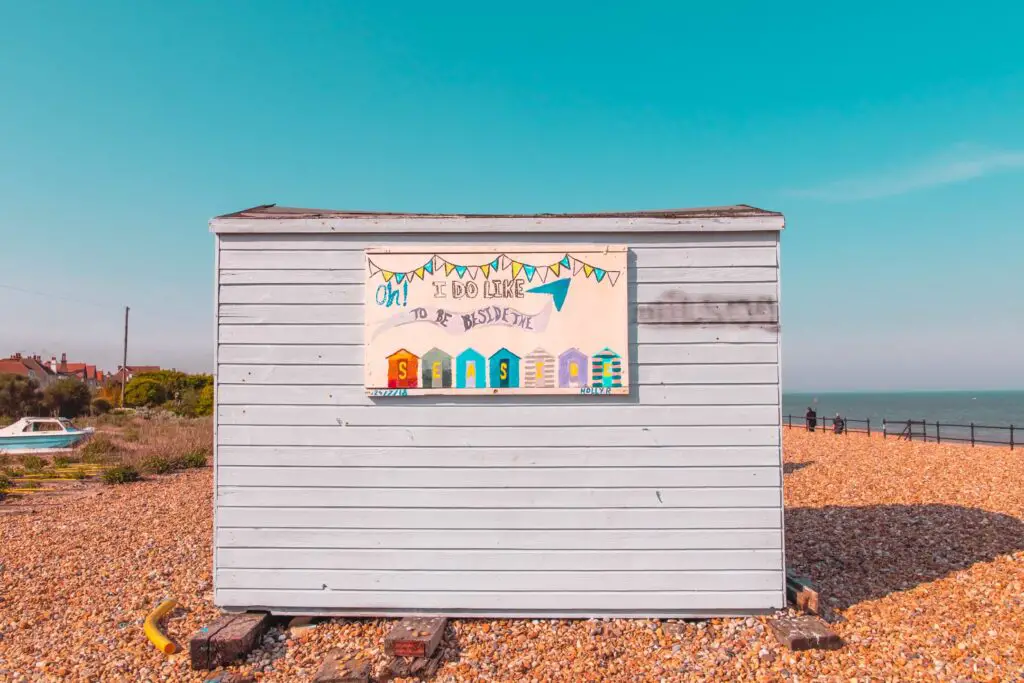 A beach hut on a shingle beach on the walk from Dover to Deal. The sky is bright blue with no clouds.