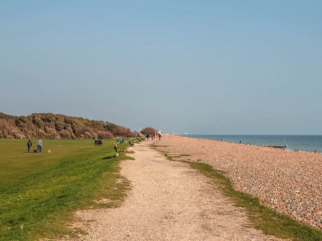 A gravel path with green to the left and shingle beach to the right on the walk towards Worthing from Littlehampton. 