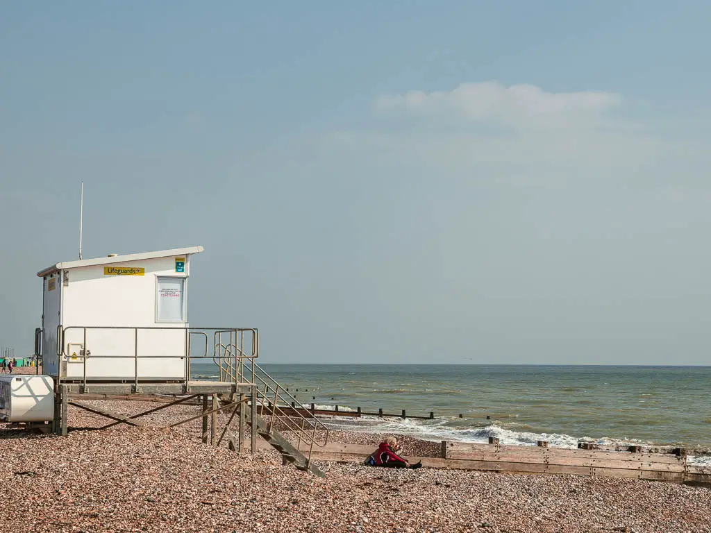 A white life guard building on the shingle beach on the walk in Littlehampton.