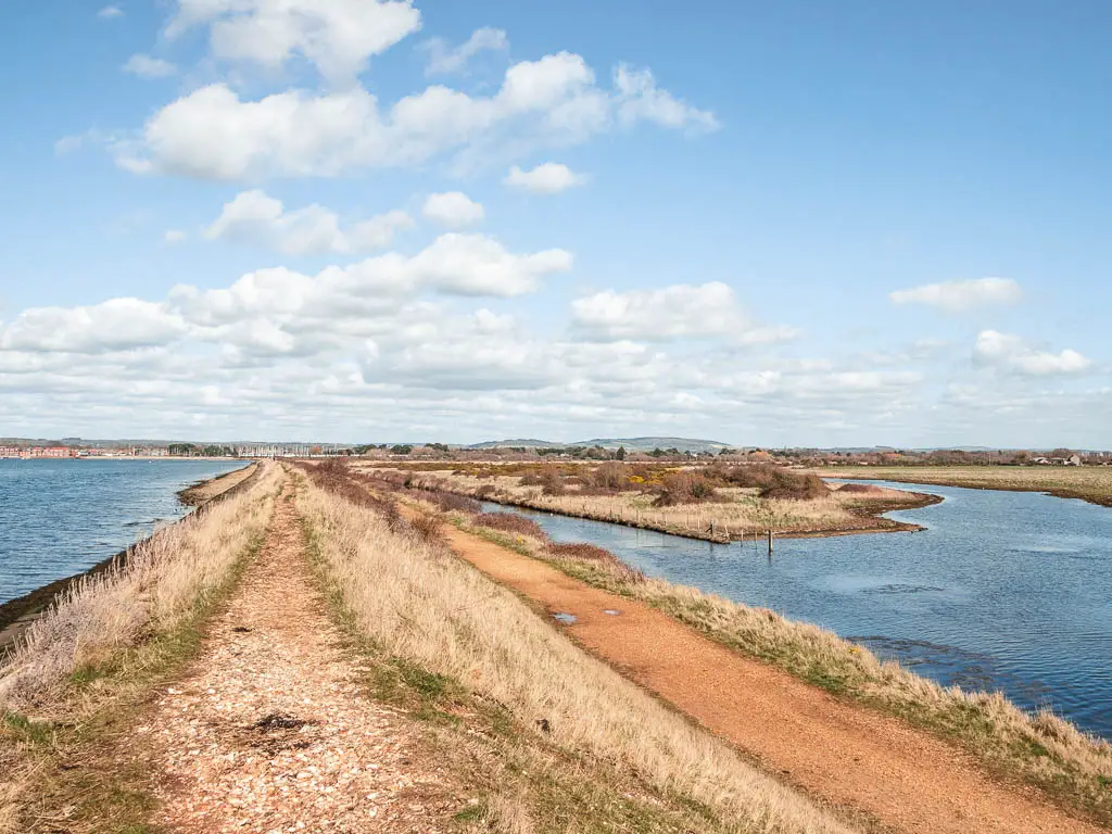 The long ridge path with the sea to the left and a lake to the right on the circular Thorney Island walk.