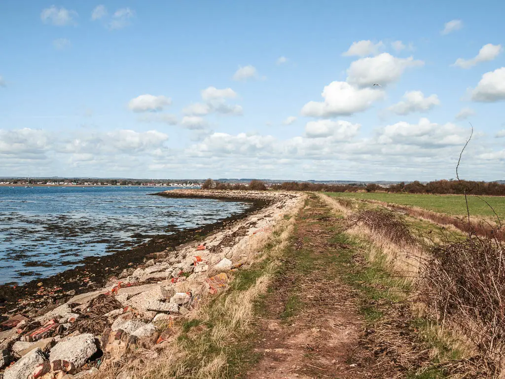 A dirt path with rocks to the left leading to the blue sea.