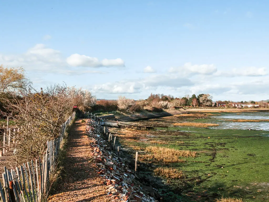 A gravel path on the left with the sea bed at low tide to the right on the walk off Thorney Island.