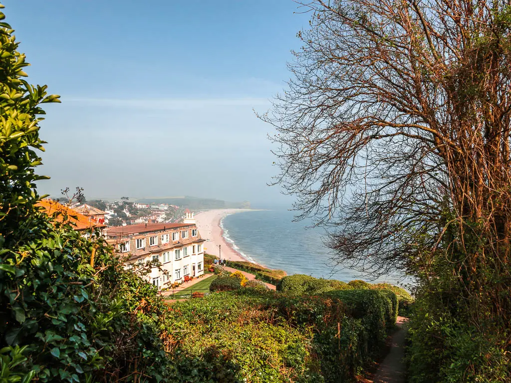 Looking over the hedges to a white coloured house and Budleigh Salterton beach ahead at the end of the coast path walk from Exmouth.