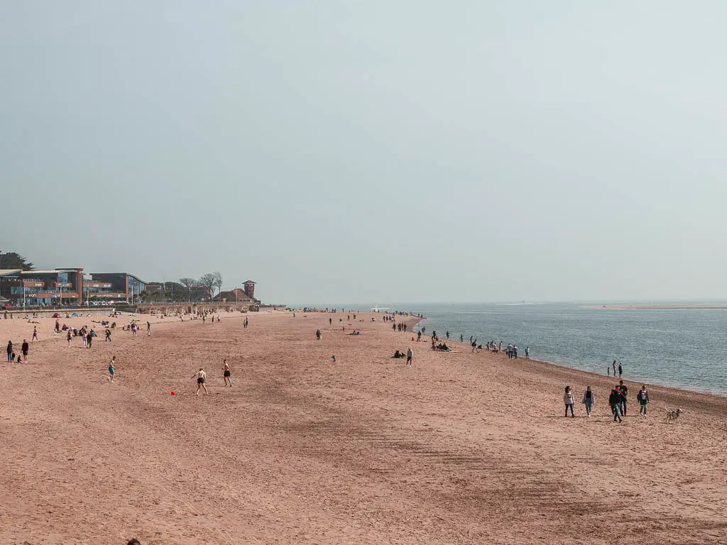 A long stretch of sandy beach with lots of people on it in Exmouth. 