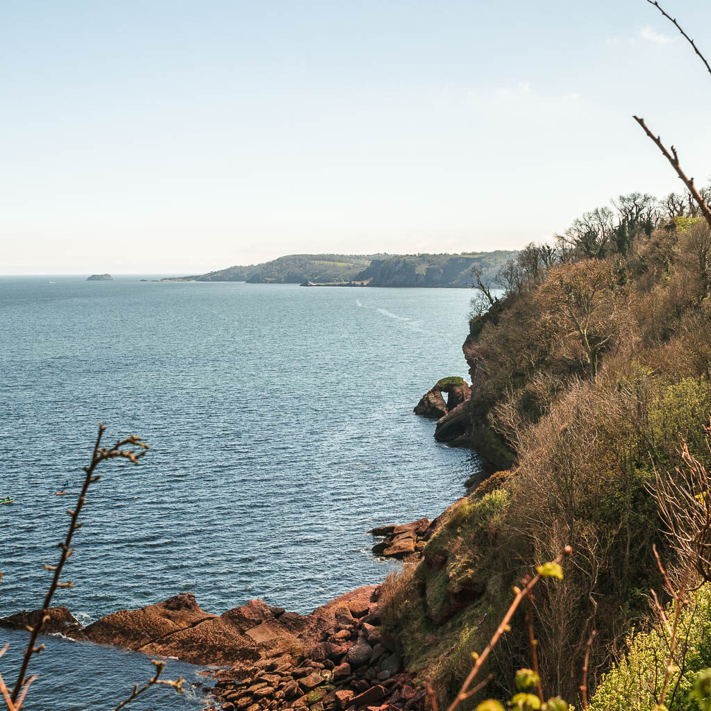 Looking along the cliffside to a rock arch on the coastal walk from Babbacombe to Teignmouth.