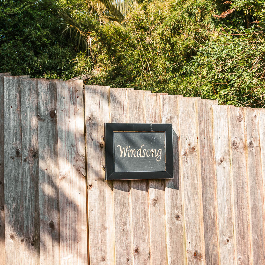 A wooden fence with a sign saying 'windsong' on it.