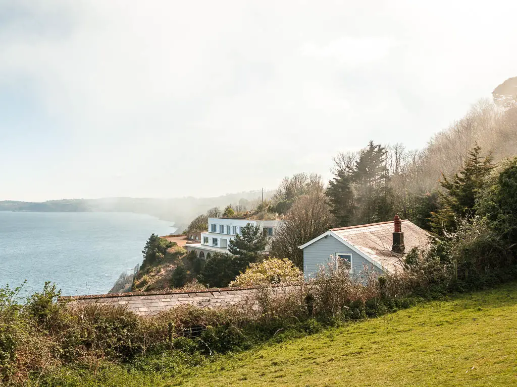 Looking towards two clifftop houses on the Babbacombe to Teignmouth coastal walk. There is mist hanging over the houses. 