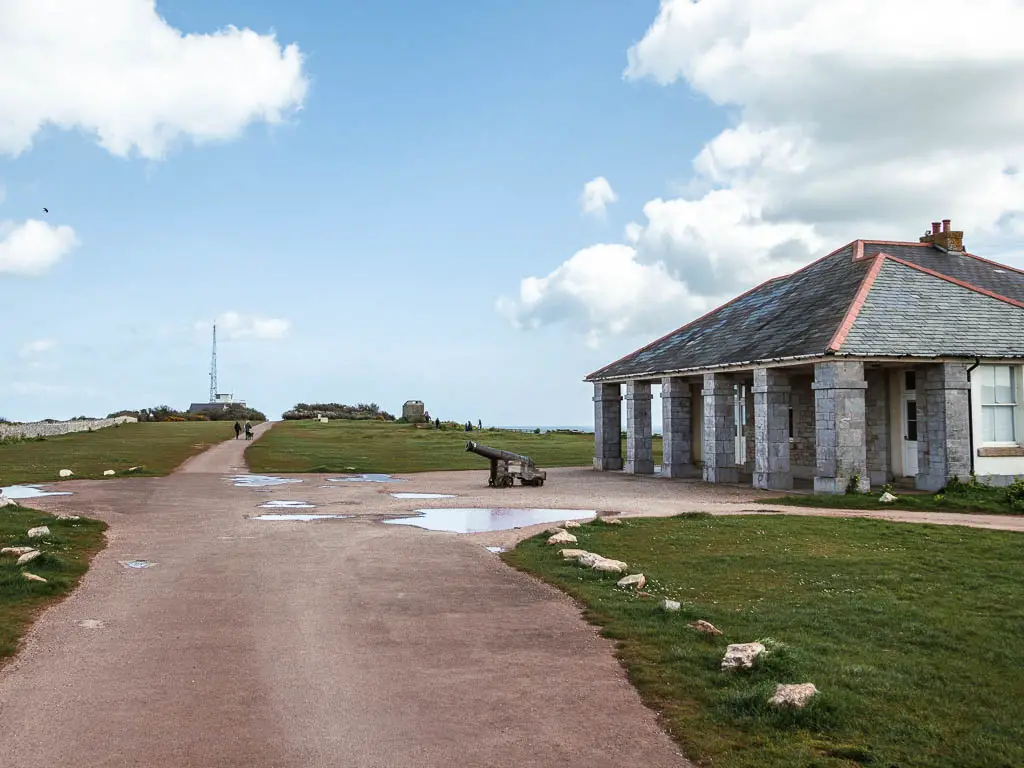 A wide path, with a cannon ahead to the right and a stone building behind it.