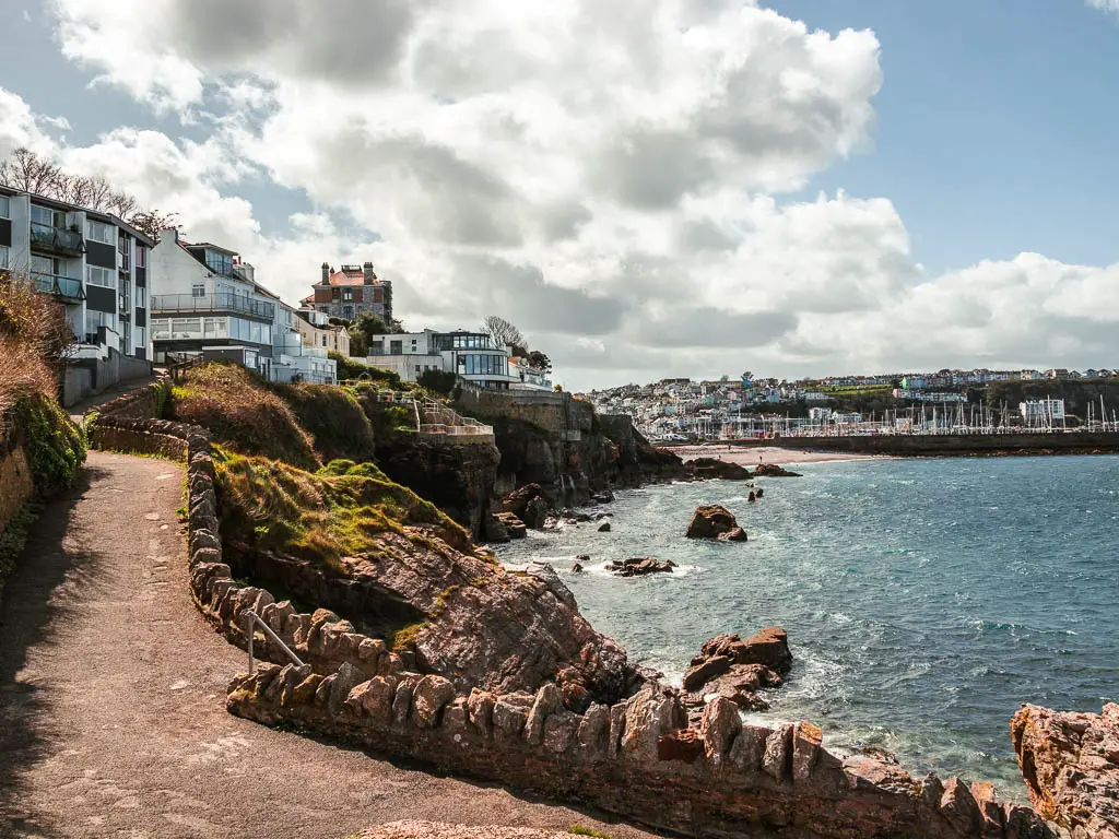 The path leading uphill to the left and the sea to the right with a view towards Brixham on the walk towards Berry Head.