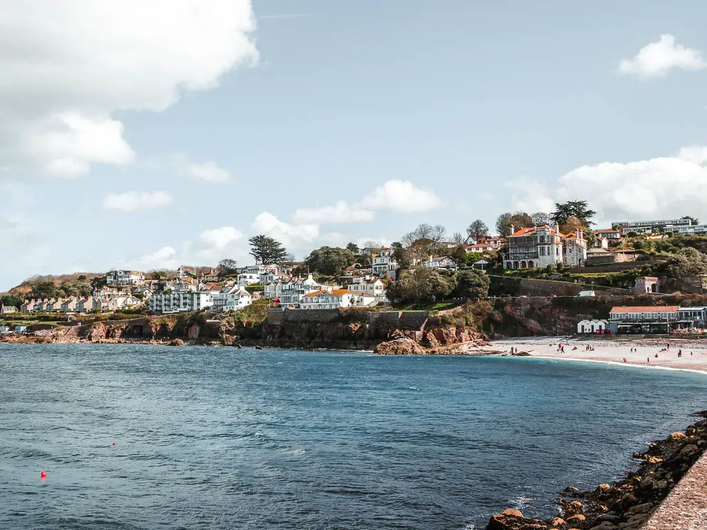 Looking across the blue sea towards the cliffs and houses of Brixham at the end of the walk from Berry Head.