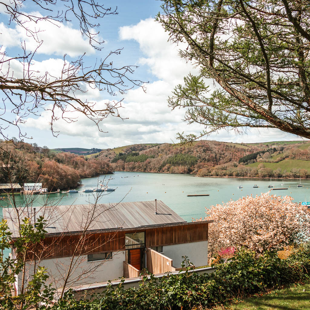 Looking through a gap in the trees and over the rooftops to the river dart on the Dartmouth Dittisham walk. 