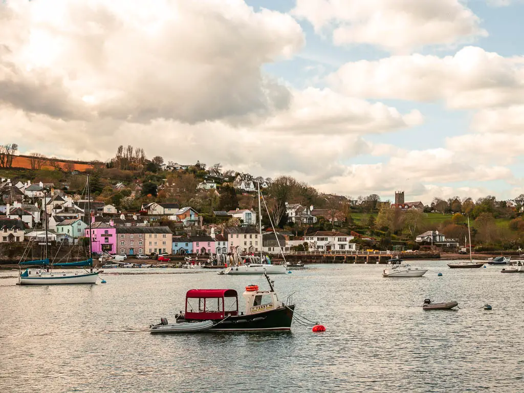 Looking across the River Dart, from Greenway towards the colourful buildings of Dittisham on the walk from Kingswear and towards Dartmouth. There are a few little boats on the river.