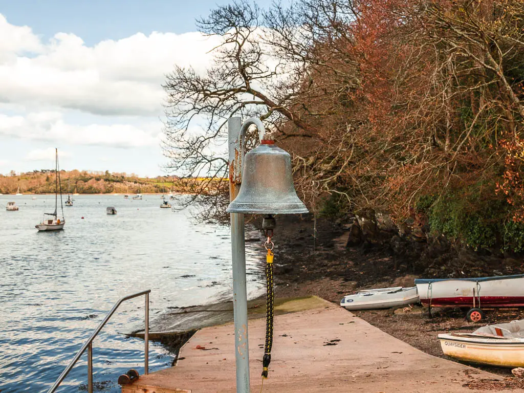 A large bell with a rope next to the river Dart on the Dartmouth Dittisham walk.