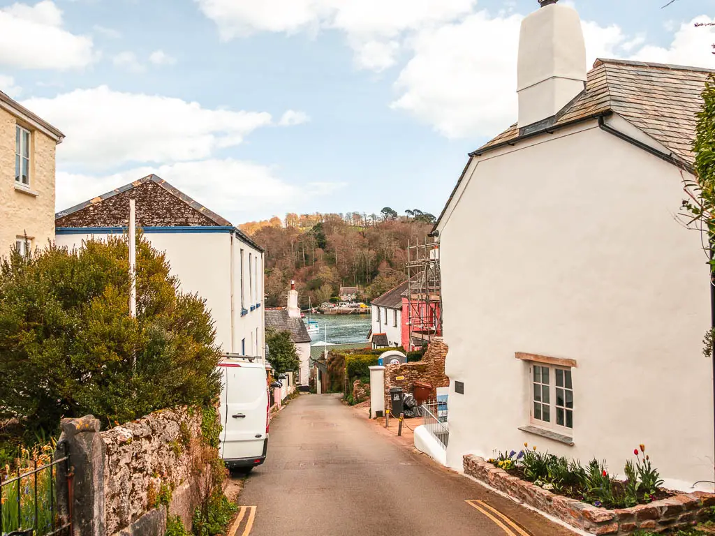 Looking down a small road lines with quaint houses in Dittisham, with the river just visible at the bottom.