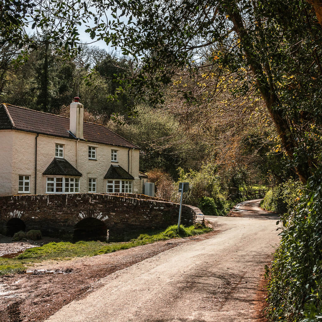 A road leading to a small white stone walled house.