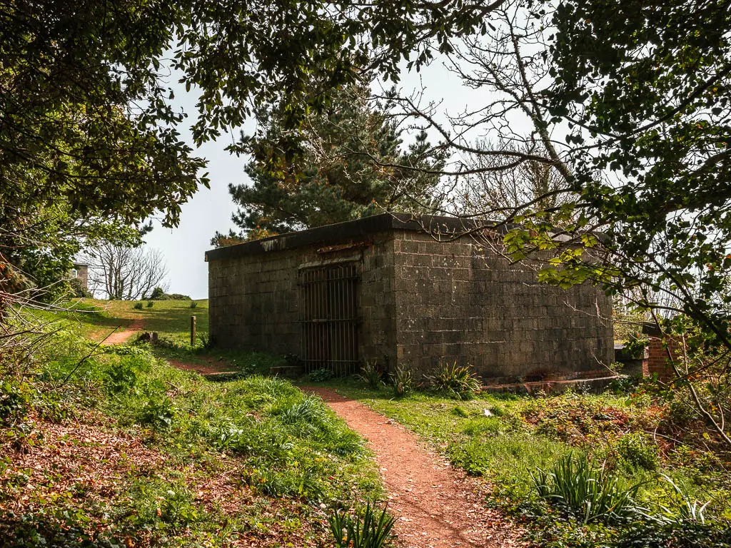 A stone square building with the trail running past it on the left. 