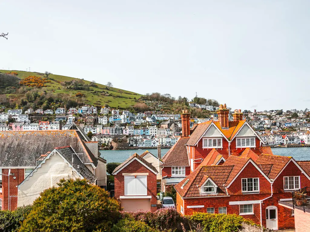 Looking towards red coloured buildings with a view to the river dart and the rows of colourful houses of Dartmouth on the other side.