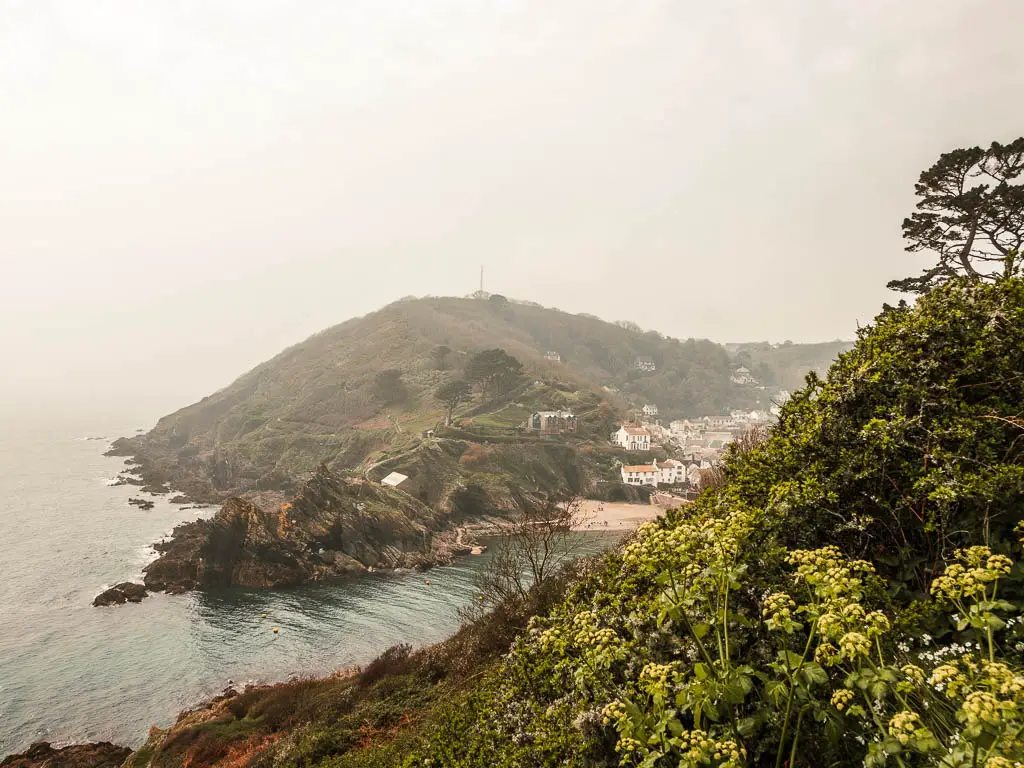 A view into Polperro with the rocks jutting out on the peninsular at the end of the coastal walk from Looe. It is a foggy day.