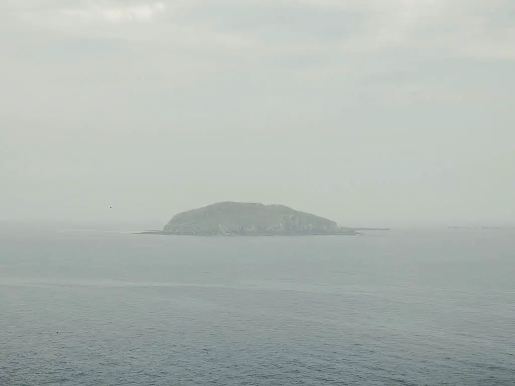 Looe Island out at sea, barely visible through the fog, on the coastal walk to Polperro.