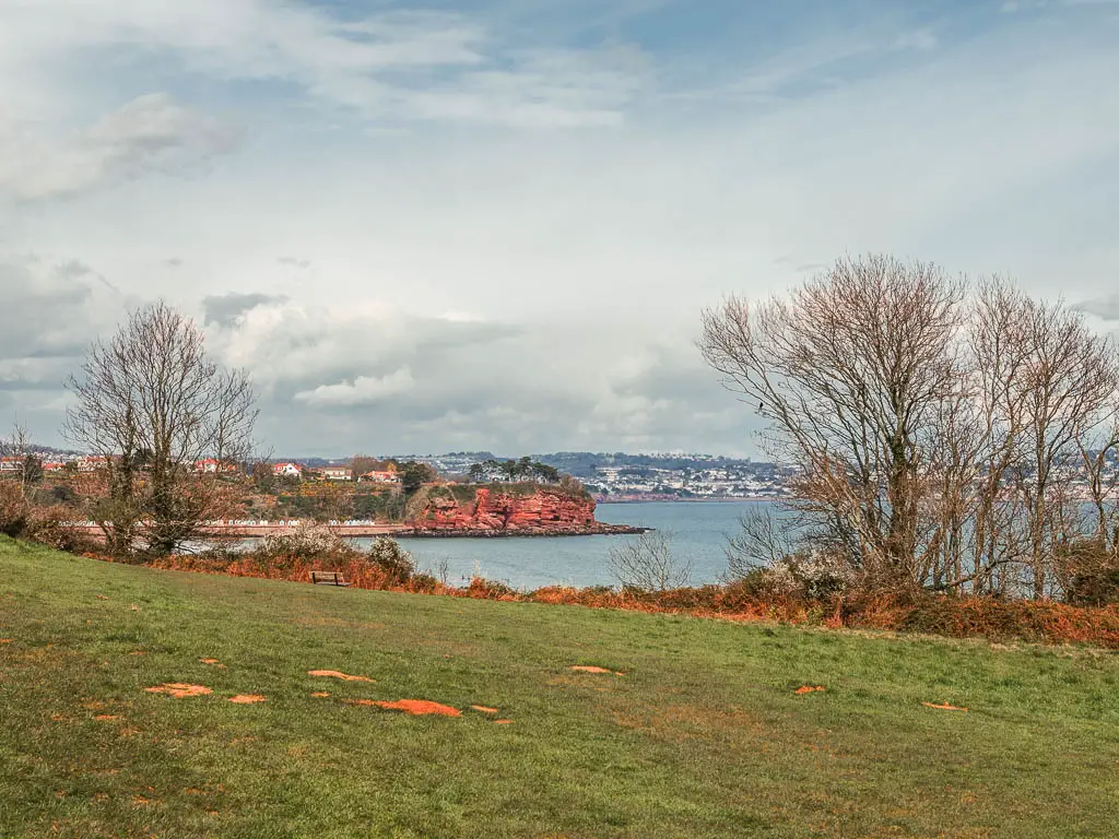 Looking across the green towards the sea and the red cliffs on the other side.