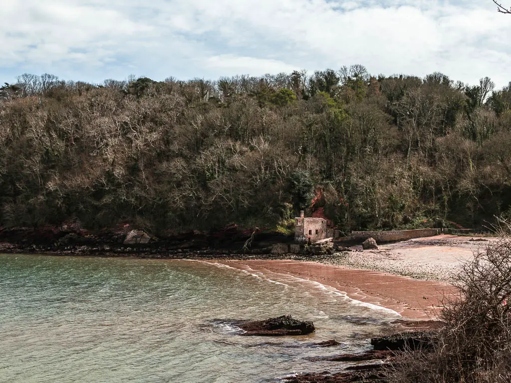 Looking down to a beach cove and a running on the other side nestled in the trees on the walk from Paignton to Brixham.