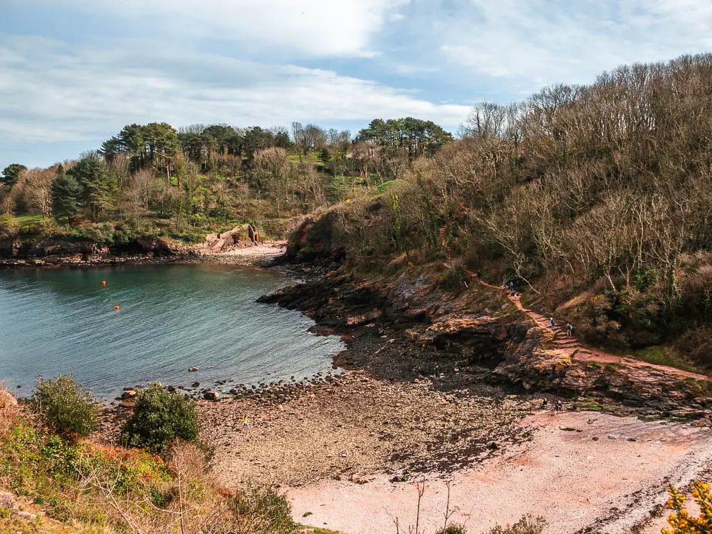 Looking down to a sandy beach cove and surroudned by rugged landscape and trees.