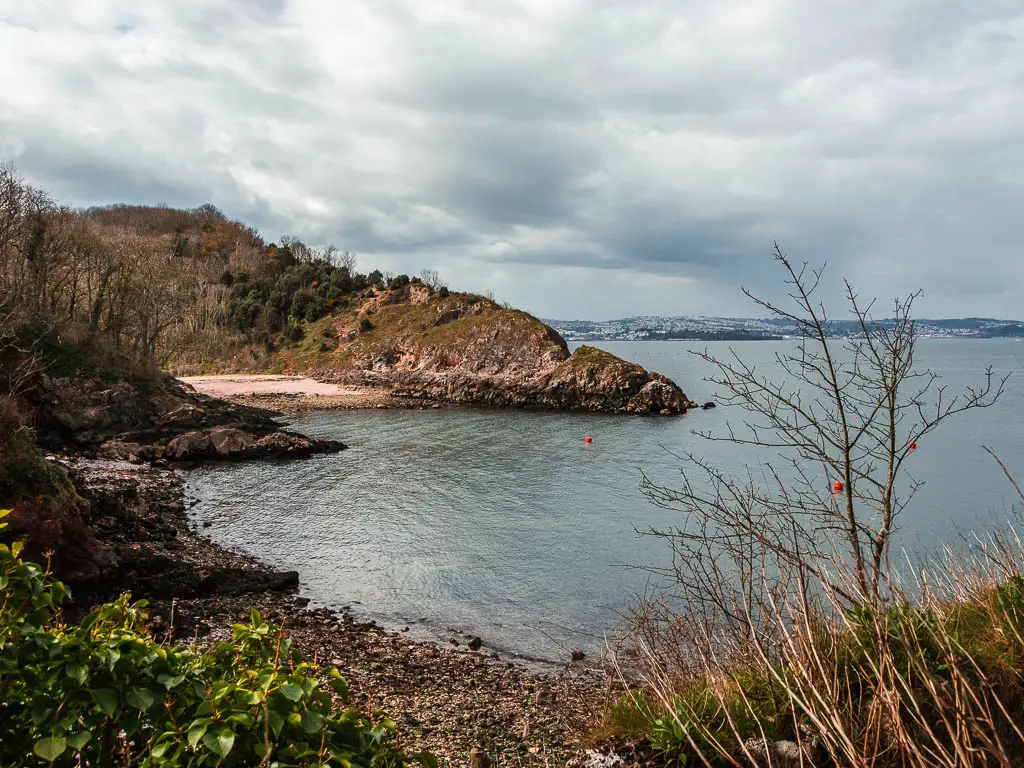 Looking across the sea towards peninsula and beach cove near the end of the coastal walk from Paignton to Brixham.