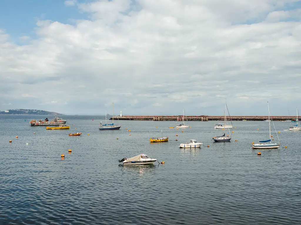 The blue sea with ripples and a few boats dotted about in Brixham Harbour.