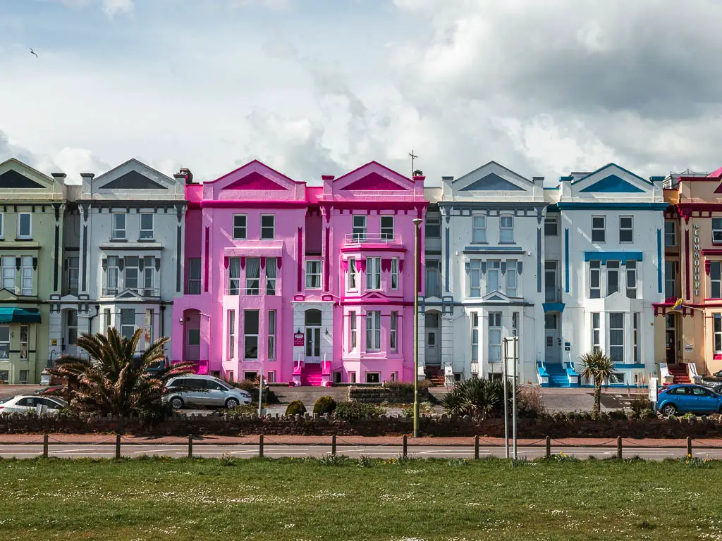 The pink and pale blue facades of the tall houses lining the road in Paignton.