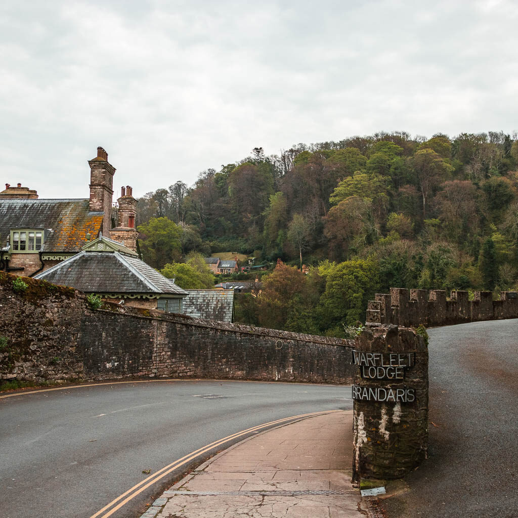 The road as it curves to the right, lined with a stone wall on both sides.