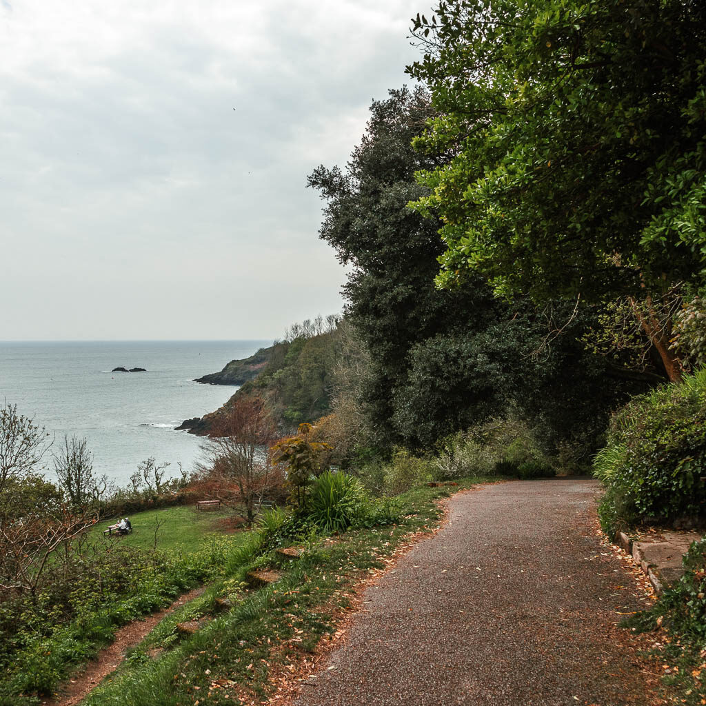 A wide path on the right, with a grass hill leading down to the left and the sea beyond that.