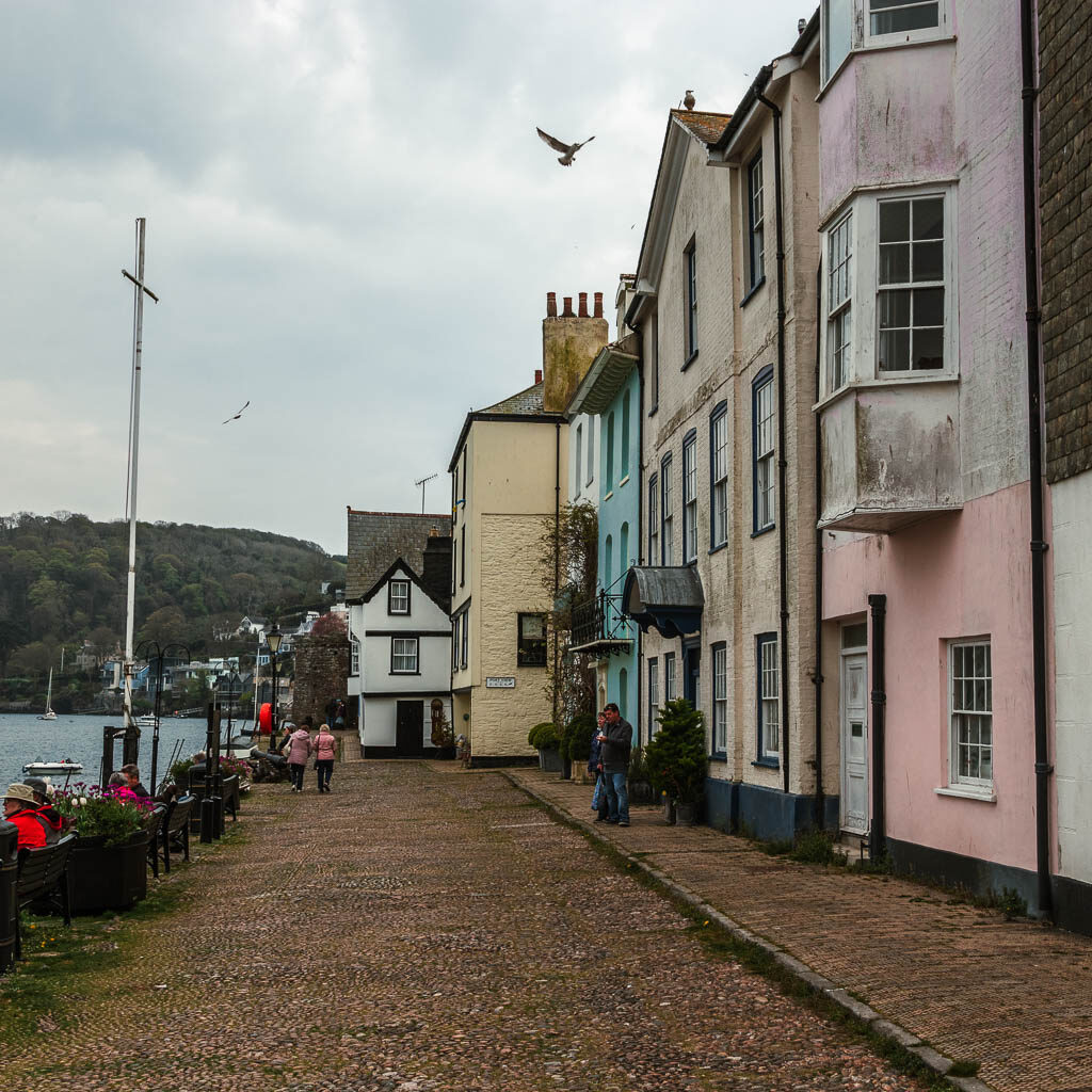 Looking along the cobble street, with pastel coloured houses on the right.