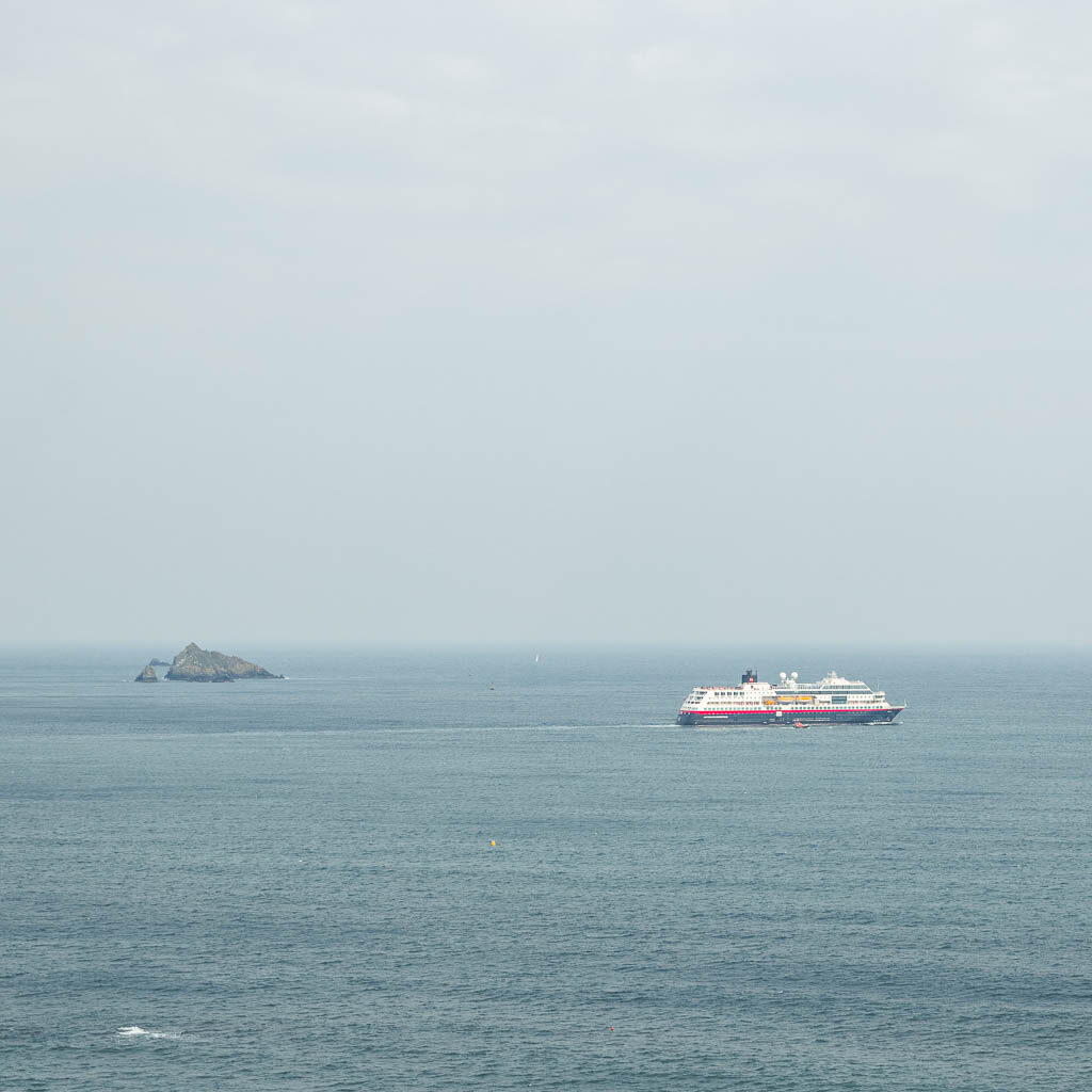 A cruise ship and sea rock out to sea.