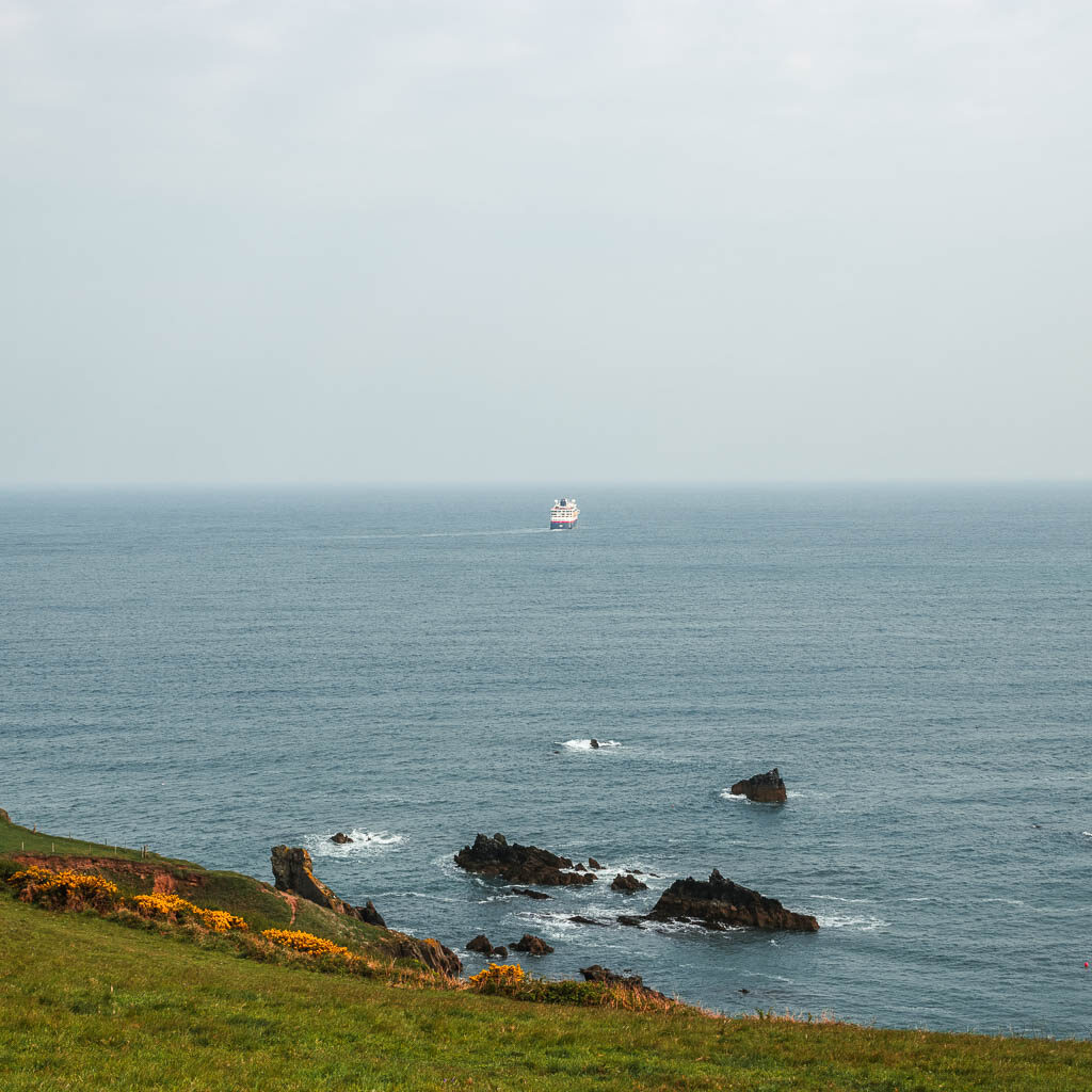 A cruise shop sailing away in the distance in the sea. 