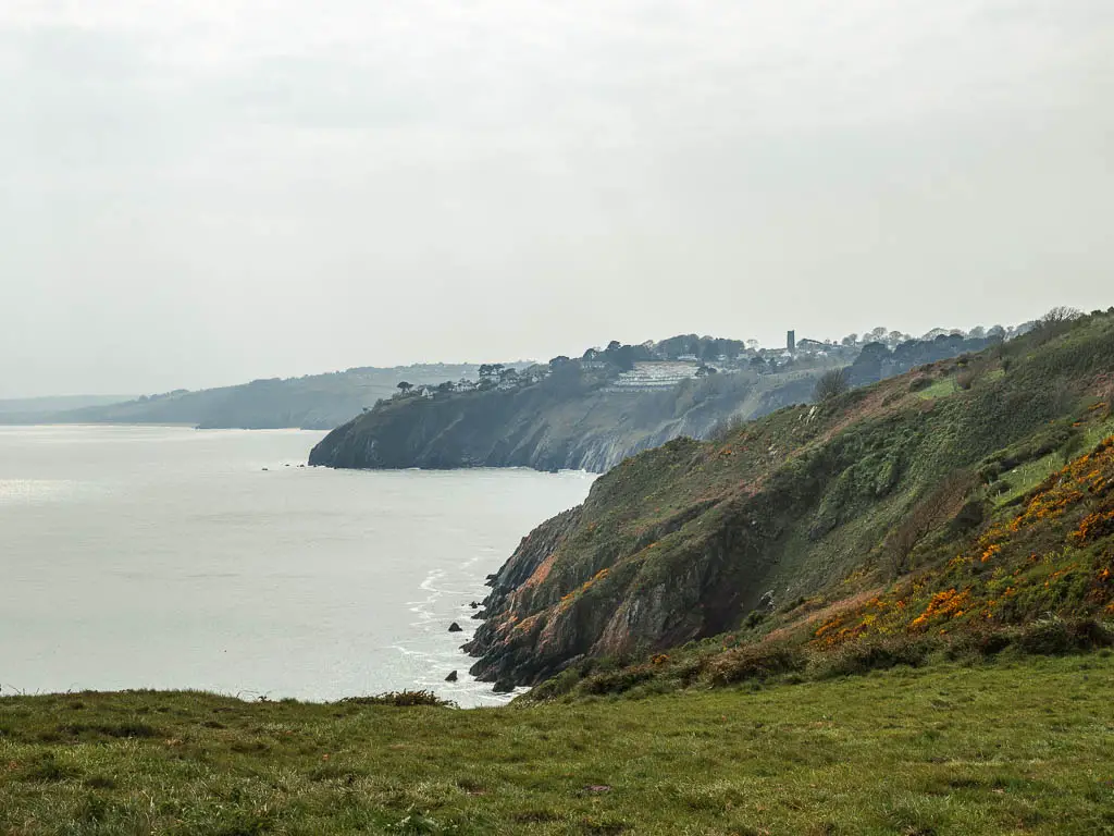 Looking along the rugged grass covered cliffs as they meet the sea on the walk from Dartmouth to Blackpool Sands.