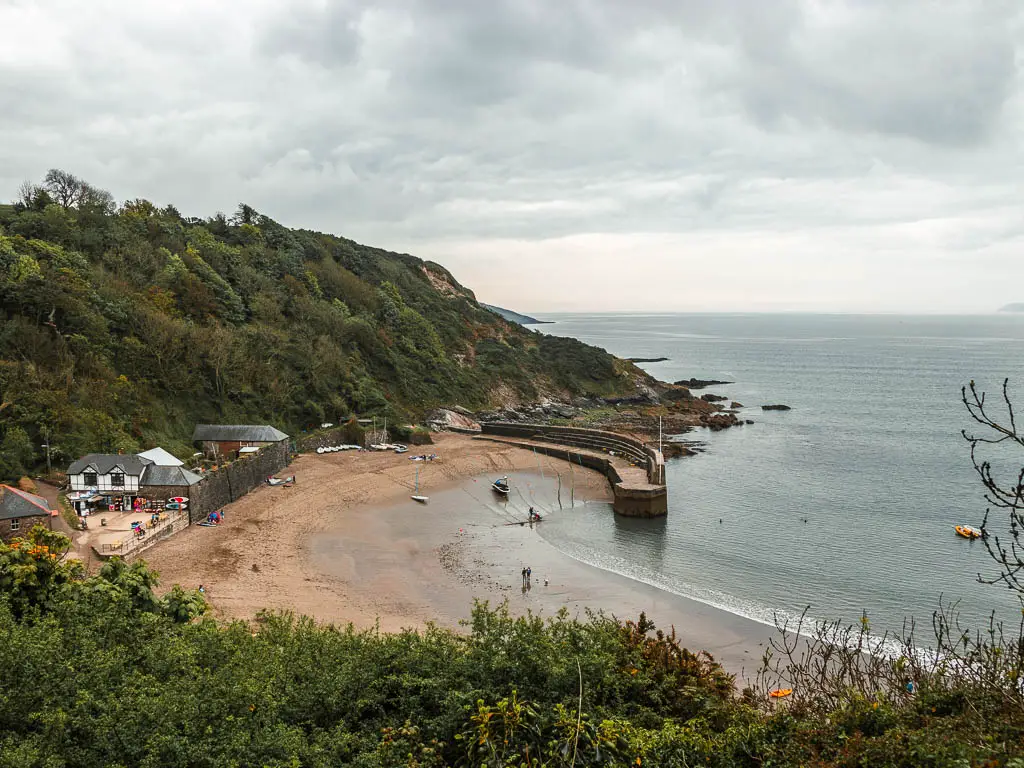 Looking down to the beach cove of Polkaris on the coastal walk from Par to Fowey. The cliff surrounding the bay is covered in trees.