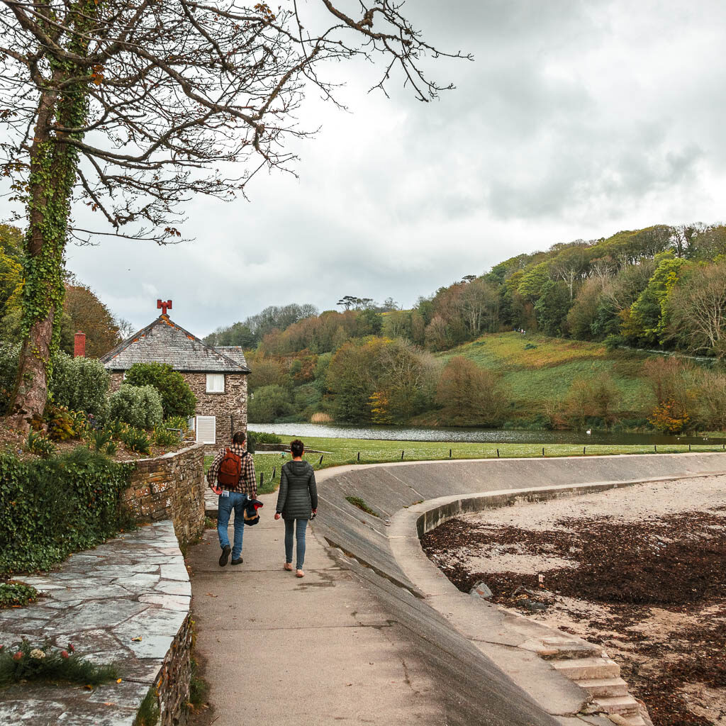 The path as it begins to curve to the right, with a small hut ahead to the left. There are two people walking on the path.