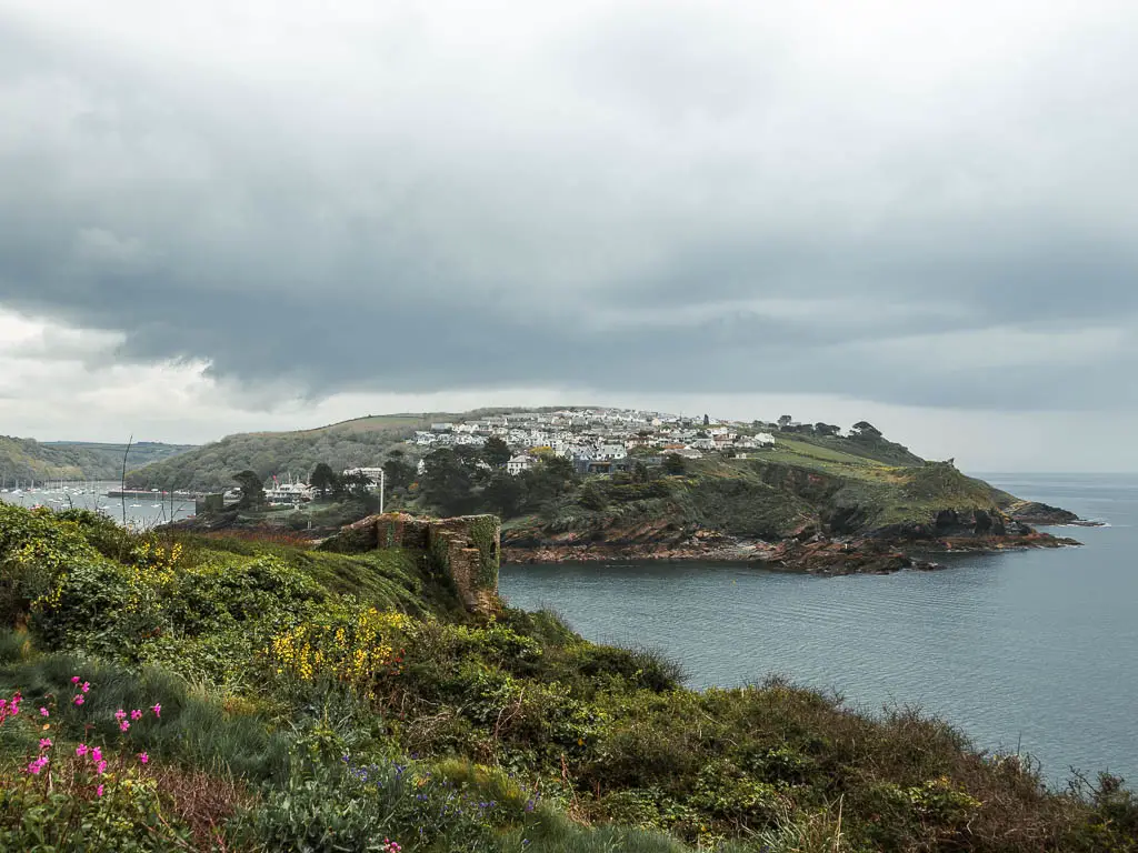 Looking across the grass and bush covered hilltop towards the sea and the Polruan peninsular on the other side. 