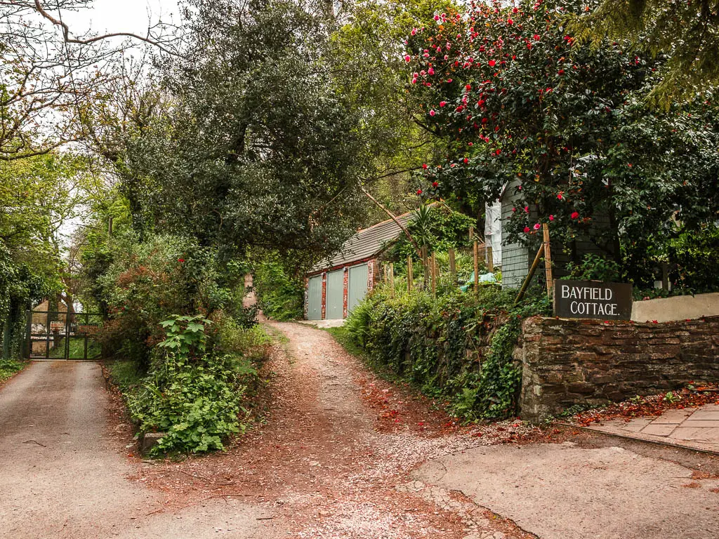 A road on the left and a path leading uphill to the right next to a sign that says Bayfield Cottage. 