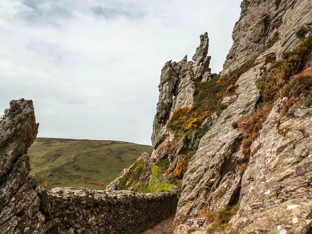 A stone wall on the left and jagged tor outcrops to the right and ahead.