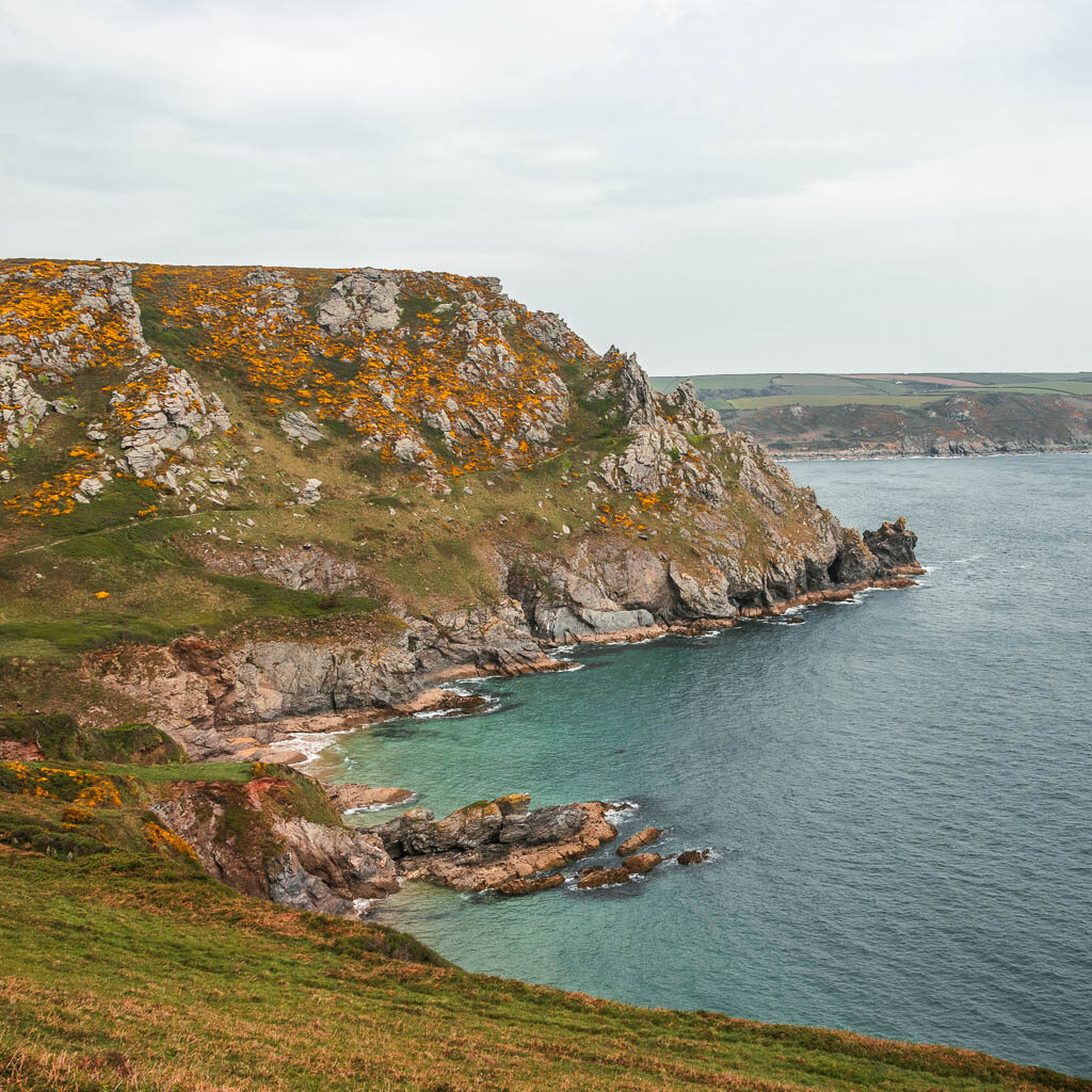 A cliff peninsular with jagged rocks on the left and the blue sea on the right.