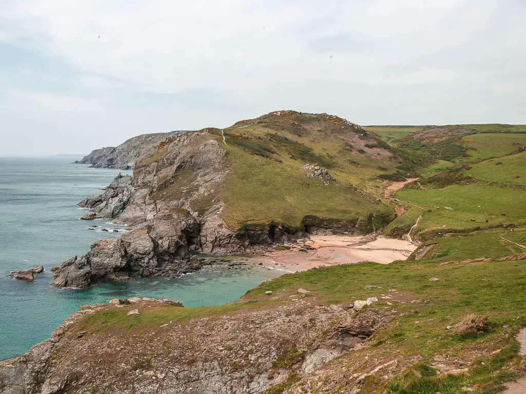 Looking down the a beach cove surrounded by rugged rocky cliffs on the coastal walk from Salcombe to Hope Cove.