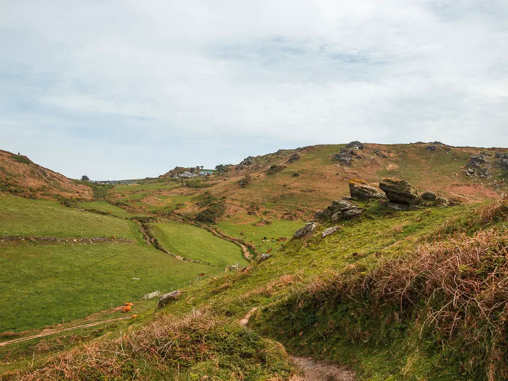 Looking down the grass covered hill into the valley and then hill on the other side.