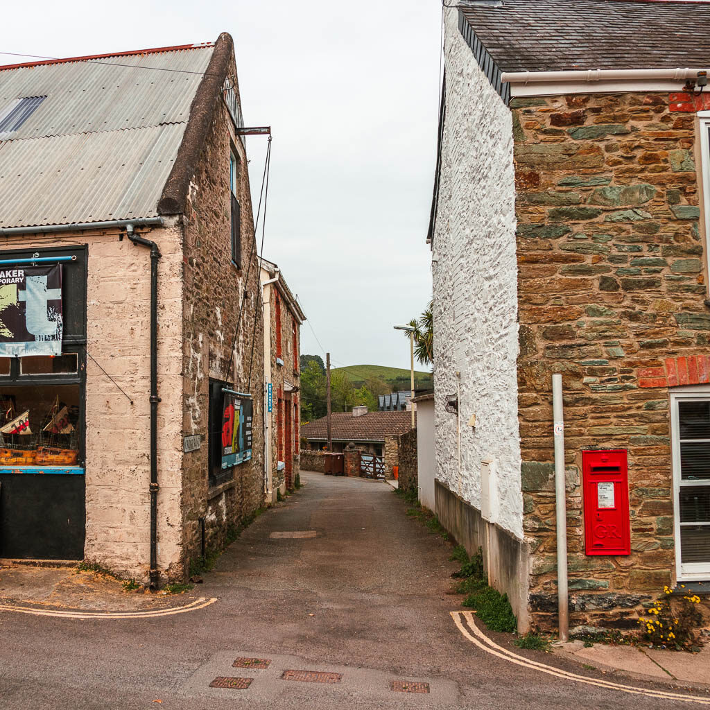 Looking down a road alleyway with buildings on both sides. There is a red telephone box on the wall of the right building.
