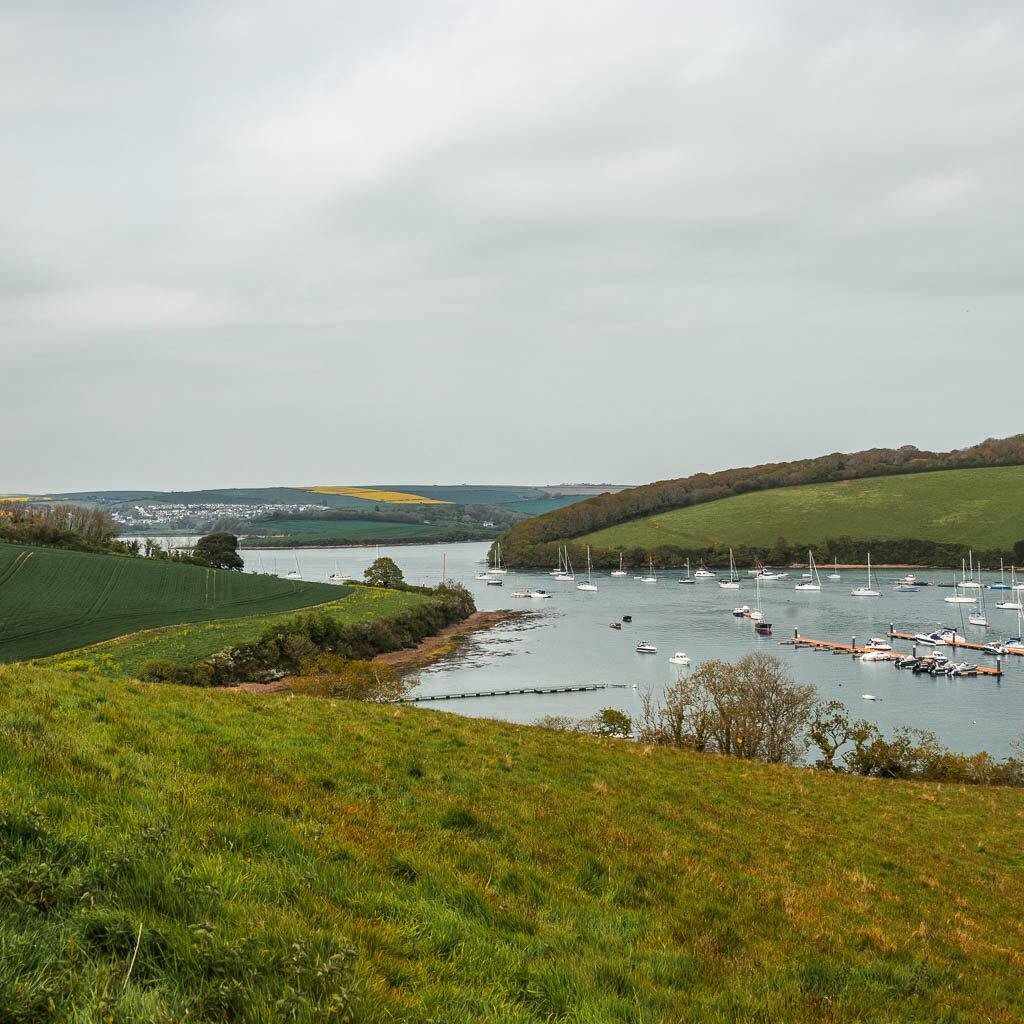 Looking along the green grass field to the estuary and lots of boats ahead.
