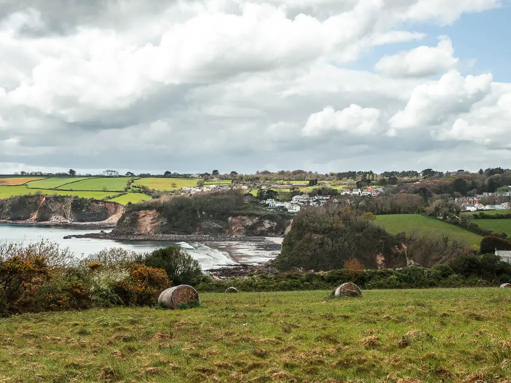 Looking down the grass field towards the cove of Charlestown, and the cliffs on the other side. 