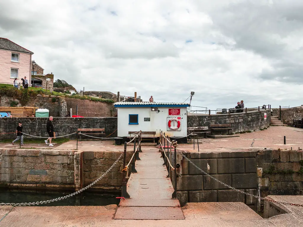 A metal bridge leading to a white shed in Charlestown harbour, at the start of the walk to par.