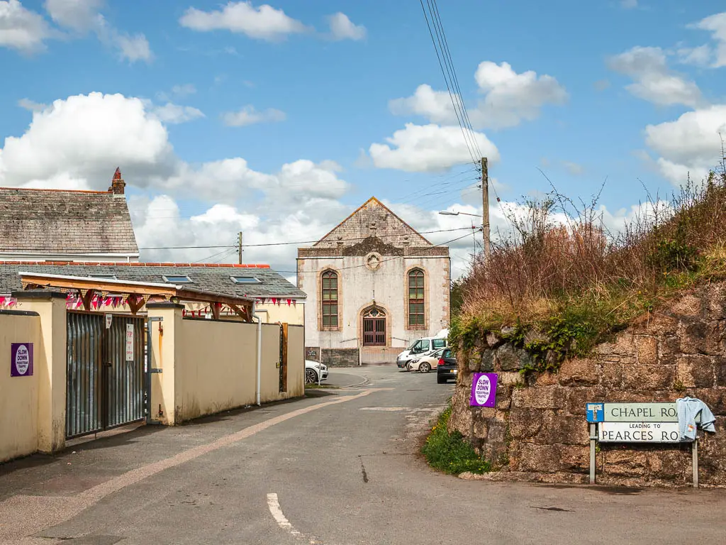 Looking along the road to some of the buildings in Par. There is a road sign saying Chapel Road, with a towel hanging off it.