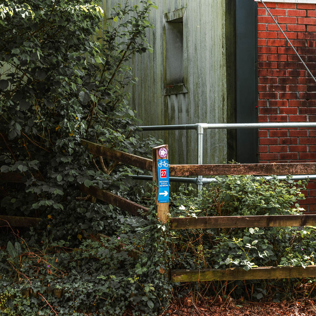 A wooden trail signpost next to a wooden fence.